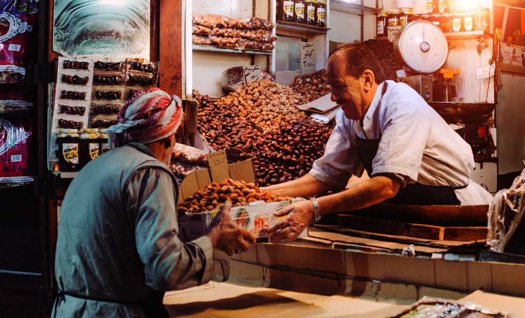 Man in a food stand passing a box to a customer.